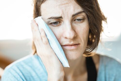 A woman holding an ice pack to her jaw | Chiropractic Ann Arbor