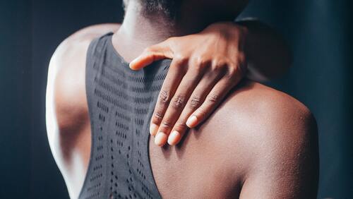 A woman holding her shoulder in pain | Chiropractor near me