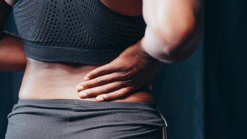 A woman holding her back in pain | Best chiropractor in Ann Arbor